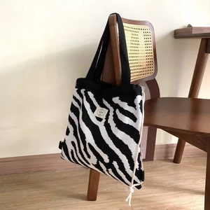 Detail einer Stricktasche mit Zebramuster, die in gemütlichem Heimdekor am Stuhl hängt