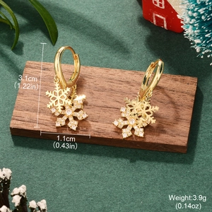 Detail showing dimensions of gold snowflake earrings with zircon on a wooden stand