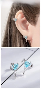 Detail of silver bow key earrings with heart-shaped blue zircon on book background