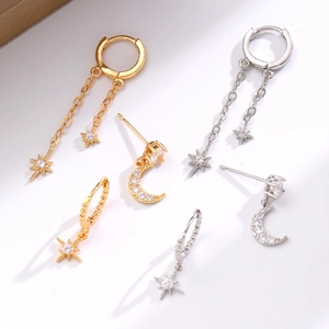 Dettaglio degli orecchini a forma di luna e stella in oro e argento con zirconi