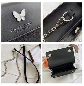 Detail of black crossbody bag featuring white butterfly decor and metal chain strap