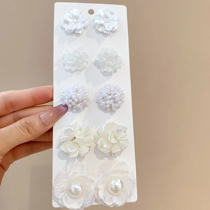Detail shot of a 5-pair white flower and pearl stud earrings set on a display card