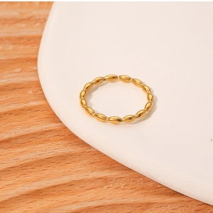 Detail of a minimalist gold beaded titanium steel ring on a white ceramic plate