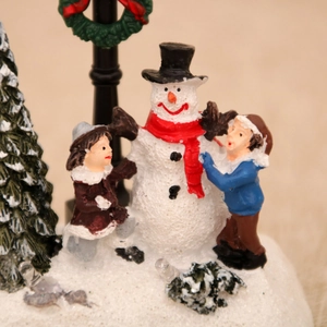 Close-up of resin Christmas miniatures with snowman and children by a street lamp