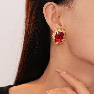 Close-up of vintage rectangular red stone earrings with gold granulated texture on model
