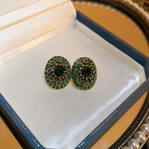 Close-up of vintage emerald stud earrings with small diamonds on a satin jewelry box