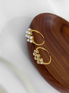 Detail of 18k gold plated open rings with faux pearls and sparkling cubic zirconia stones