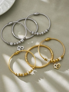 Détail de joncs en acier inoxydable or 18 carats et argent avec breloques cœur et zircon