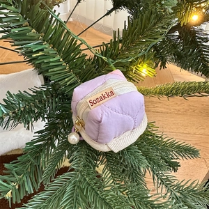 Close-up of lilac quilted case with pearl zipper pull on festive holiday background