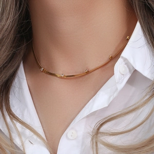 Close-up of a gold flat snake chain necklace with small cubic zirconia worn by a model