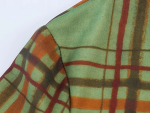 Dettaglio della spalla di un blazer a quadri vintage verde e arancione con cucitura