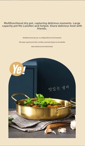 Close-up of golden stainless steel flat-bottom dry pot with dual handles on dining table