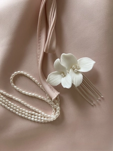 Detail of white ceramic flowers and freshwater pearls on a bridal hair comb accessory