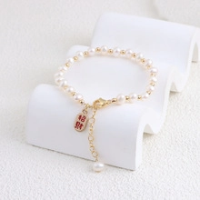 Detailed macro view of natural freshwater pearl bracelet with lucky charm and gold clasp