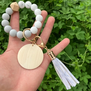 Close-up of marble silicone bead bracelet with wooden pendant and white tassel