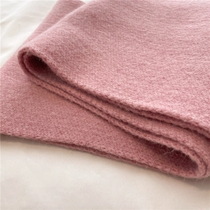 Close-up of soft pink knitted wool fabric texture showing warm plush material detail