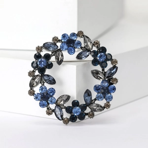 Sparkling rhinestone flower wreath brooch with blue and grey crystals on white background