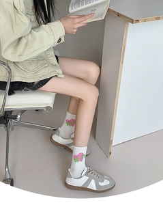 Close-up of white mid-calf socks featuring cute pink and green heart patterns on models