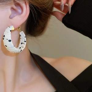 Close-up of model wearing large white and black polka dot fabric-wrapped hoop earring