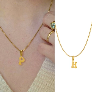 Detail view of gold-plated chunky letter pendants P and H on delicate ball chains