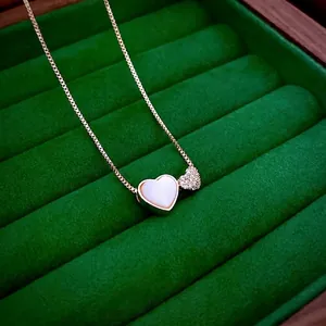 Rose gold heart necklace with white shell inlay and zircon accents on green velvet