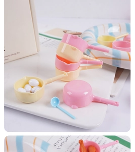 Miniature dollhouse kitchen ladles and colorful plastic pans in pastel pink and blue