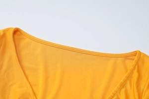 Détail du col d'un t-shirt jaune à manches longues avec des coutures à double aiguille