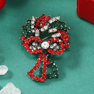 Christmas wreath brooch with red and green rhinestones and golden bells on dark background