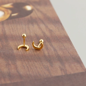 Macro di orecchini a mezzaluna dorati con chiusura a sfera su base in legno