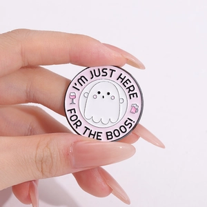 Halloween ghost enamel pin with 'I'm Just Here For The Boos' slogan held in hand