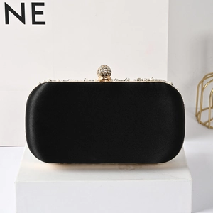 Detailed view of black satin evening bag featuring pearl trim and crystal ball clasp
