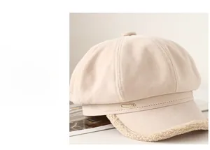 Close-up of beige suede newsboy cap featuring plush fleece brim and gold metal tag