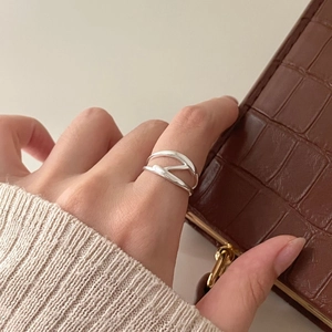 Minimalist 925 sterling silver criss cross ring worn by model with textured background