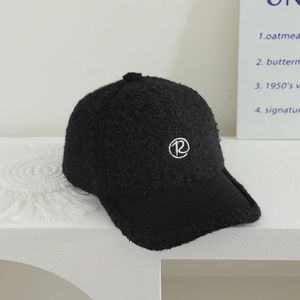 Dettaglio cappello in pile nero per bambini con ricamo R e visiera in velluto a coste