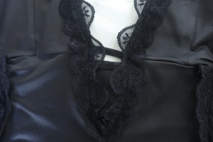 Macro detail of intricate black floral lace trim and matte fabric on a V-neck dress