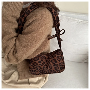Détail du sac hobo léopard avec bandoulière nouée porté sur un pull en maille marron
