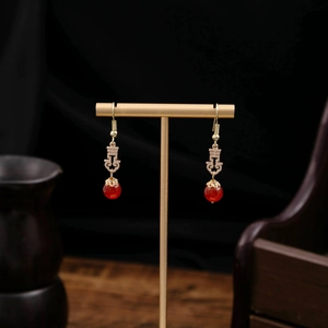 Close-up of red beads and golden Xi character earrings on a T-shaped display stand