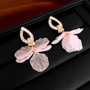 Detailed macro view of pink acrylic flower earrings with gold plating and white zircons