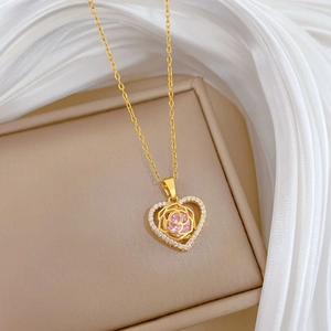 Detailed close-up of a gold heart pendant with pink gems and white diamonds on silk