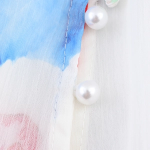 Détail de blouse en mousseline fleurie avec boutons perlés et imprimé dégradé bleu