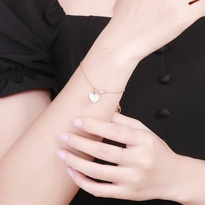 Detail of gold heart charm bracelet with sparkling crystals on a female model