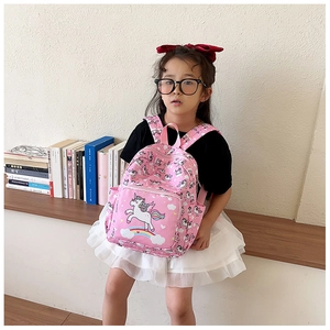 Pink unicorn backpack for girls shown on a child in a cozy indoor learning setting