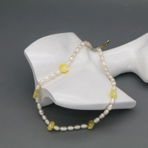 Detail of freshwater pearl necklace with yellow flower accents on a white mannequin bust