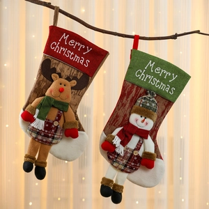Hanging oversized Christmas stockings with reindeer and snowman plush figures and plaid patterns