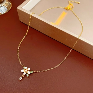 Dettaglio di una collana placcata in oro con ciondolo a fiore in smalto bianco