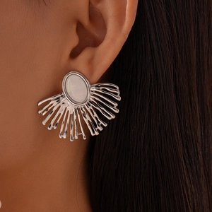 Macro shot of silver fan-shaped coral earrings with white oval stone on ear