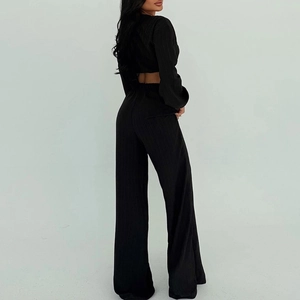 Détail du cardigan noir plissé et du pantalon taille haute, vue de dos du costume