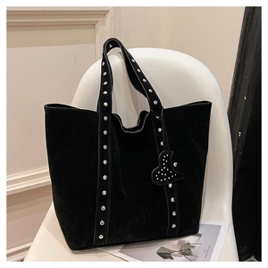 Detailed view of a black tote bag with silver studs and heart charm on a chair