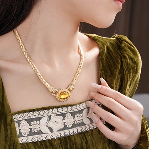 Close-up of vintage snake chain necklace with yellow oval gemstone and diamond accents