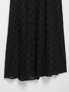 Detail of black eyelet embroidery with diamond patterns and floral cutouts on dress hem